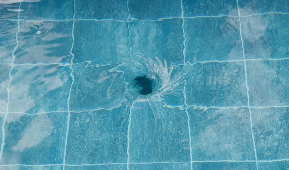 Close-up of a swirling vortex in a clear tiled pool, creating an abstract visual.